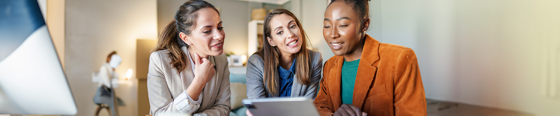 three women sitting togehter looking at a laptop