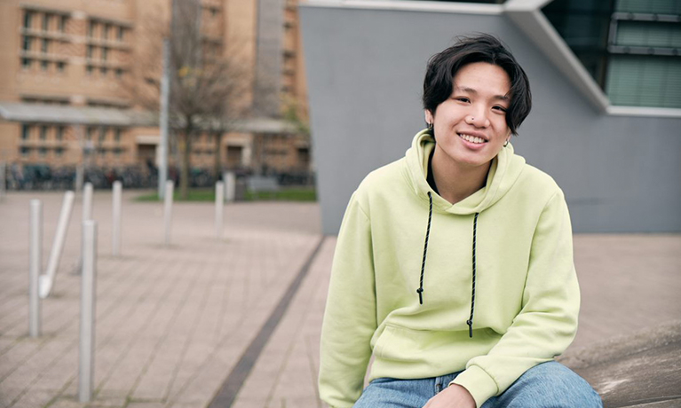 Student sitting outside on a wall