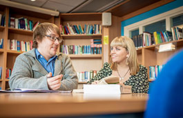 Two students sat in a library talking