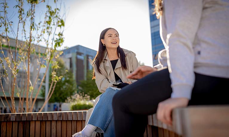 female student sat outside talking to another student