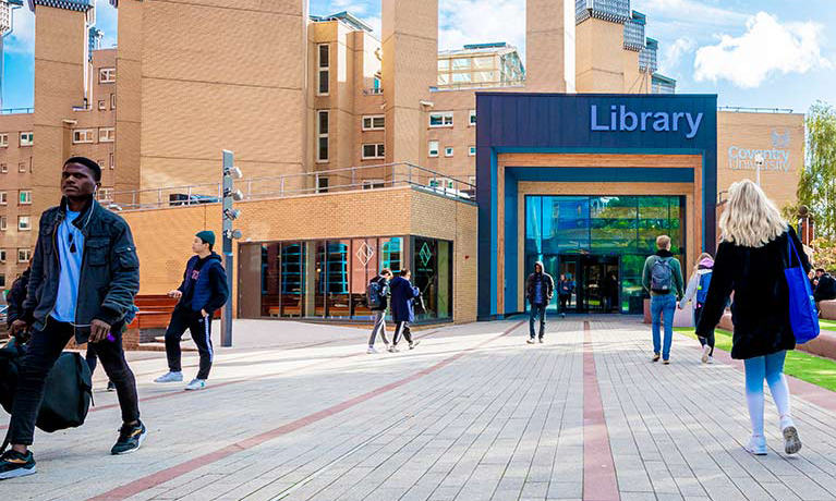 People walking in front of a building which has a big library sign