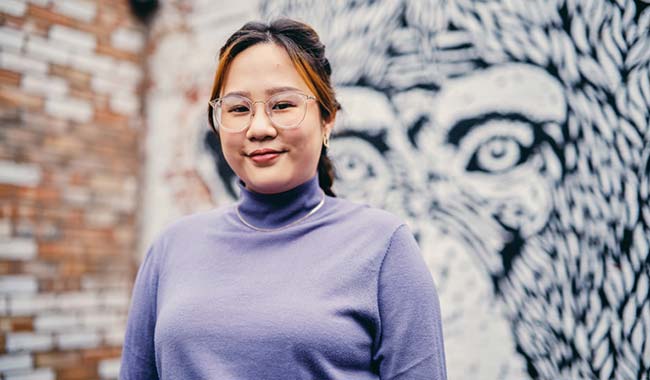 asian student standing in front of a mural