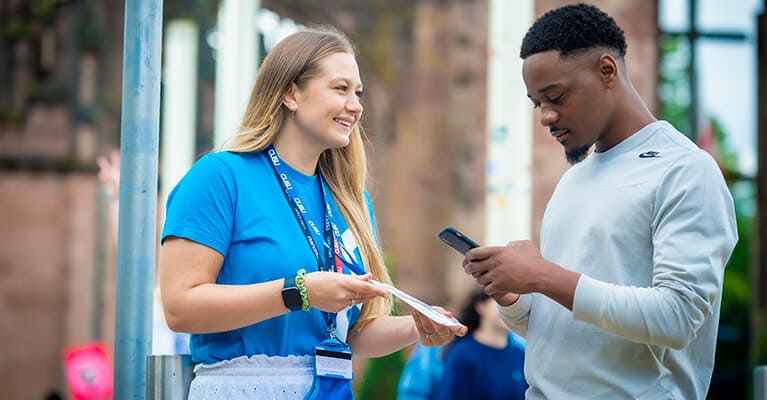 Student advisor showing a student a leaflet in the catherdral grounds