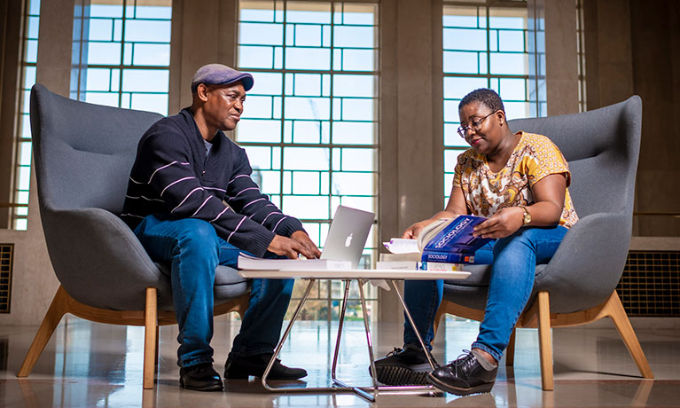 Two students sat at a table by a window talking