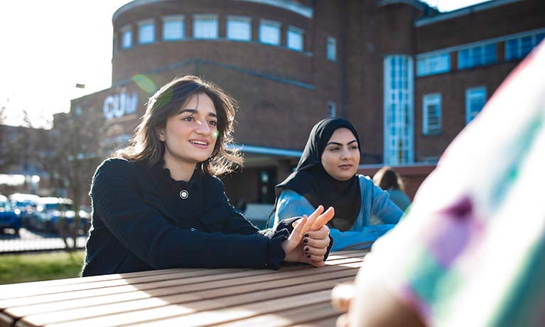 Two students sat on a bench outside