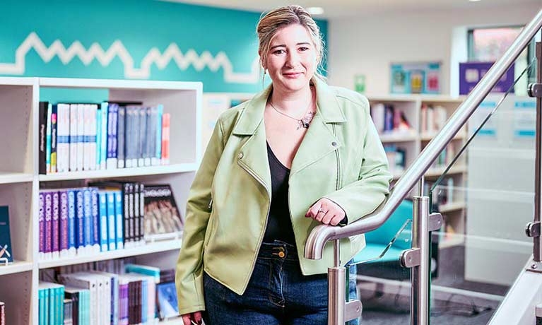 Female student stood in front of various book shelves