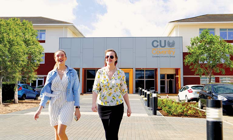 Two female students walking away from mile lane CU Coventry building