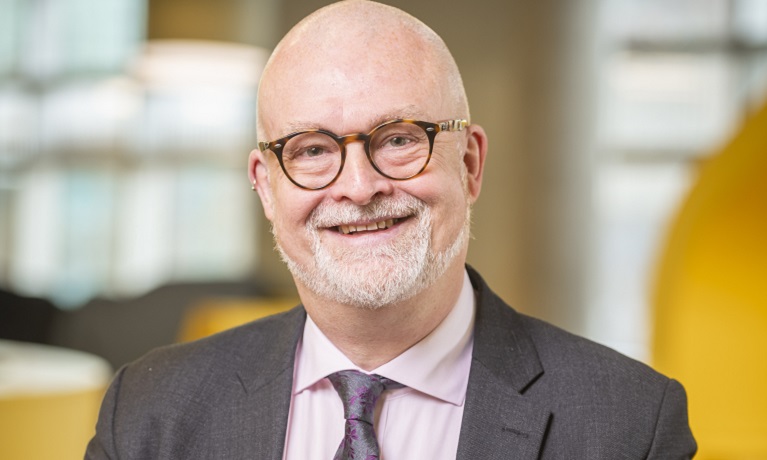 Head and shoulders shot of Ian Dunn who is wearing a suit, shirt and tie